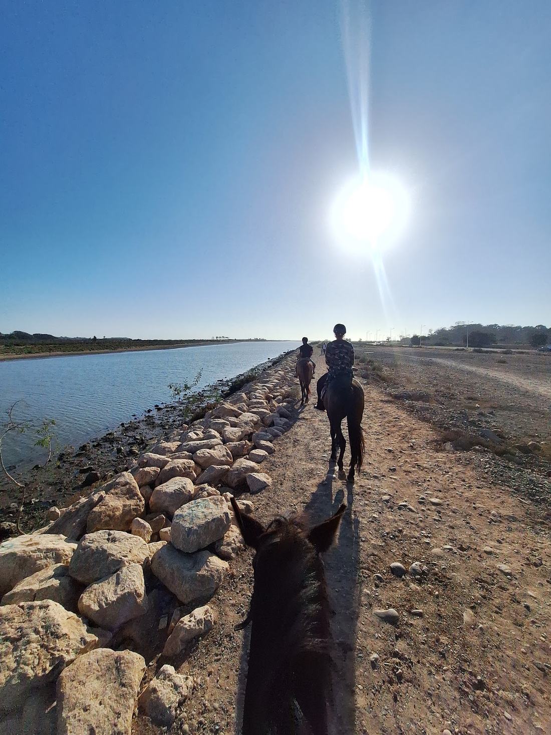 Cavalier à cheval face au soleil sur la digue au bord de la rivière près d’Agadir