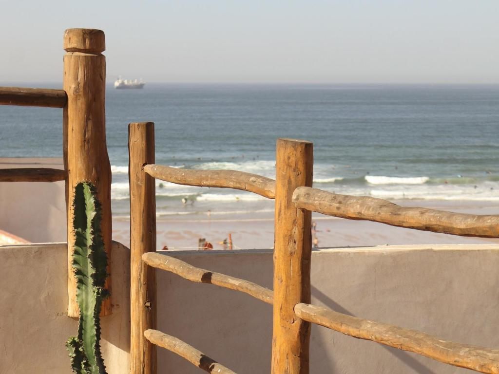 View from the rooftop: wooden rail, cactus, Anza beach and a ship on the horizon