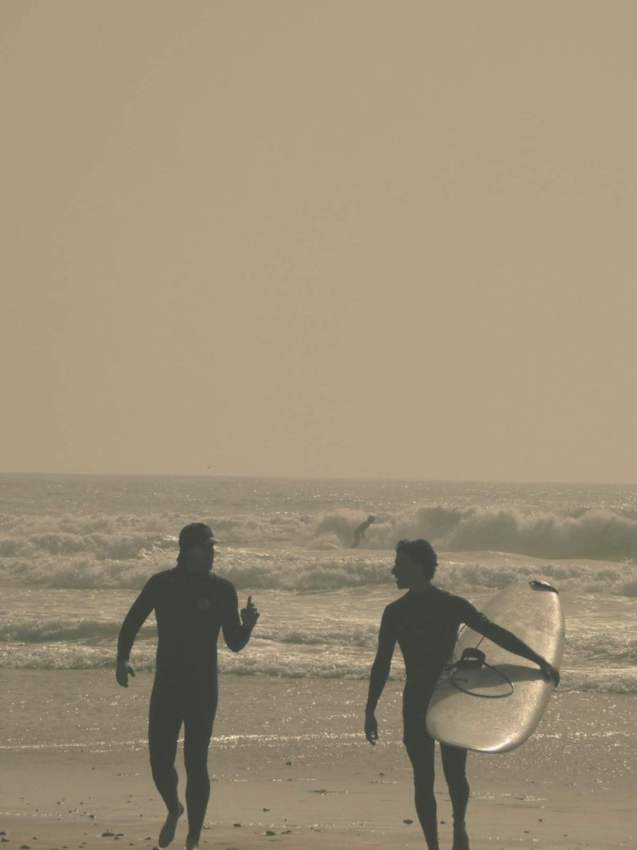 Two surfers running into the hazy sea with a board