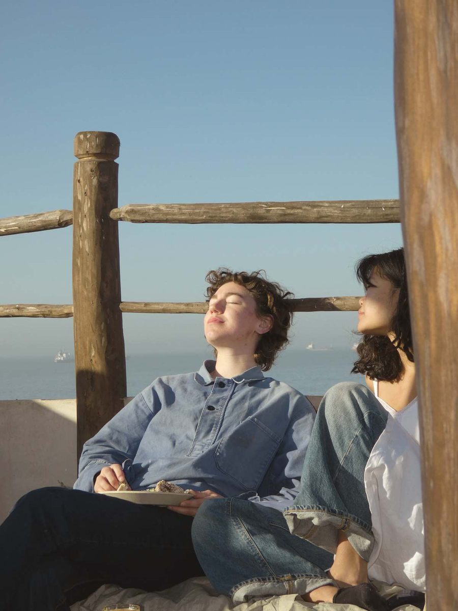 Voyageuse qui lit au soleil dans le coin banquette du rooftop